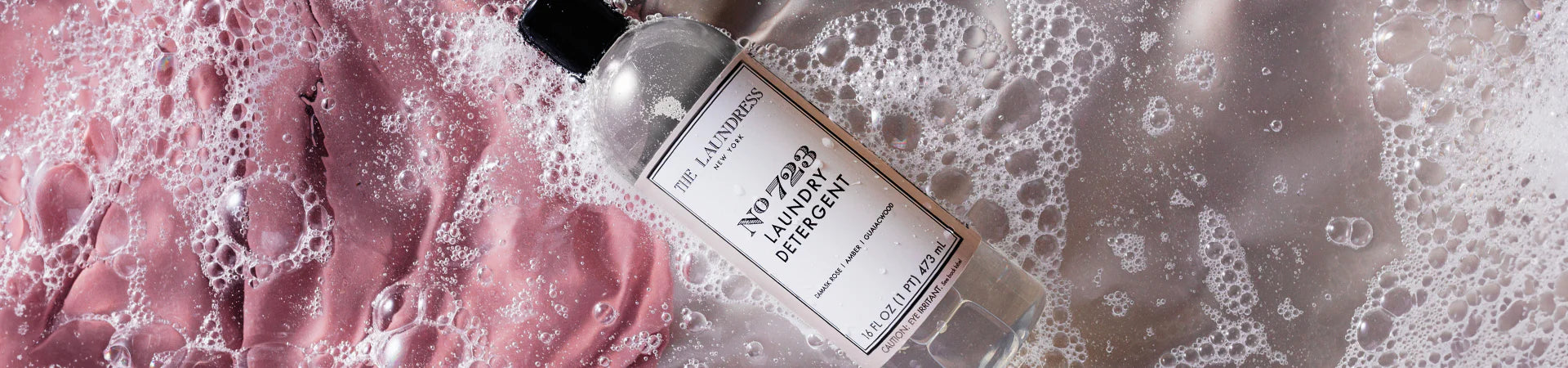 The Laundress No 723 Laundry Detergent with scents of damask rose and amber rests in sudsy water.