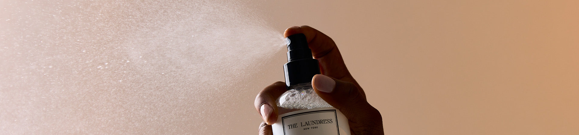 The Laundress Fabric Spray for refreshing garments is spritzed into the air.