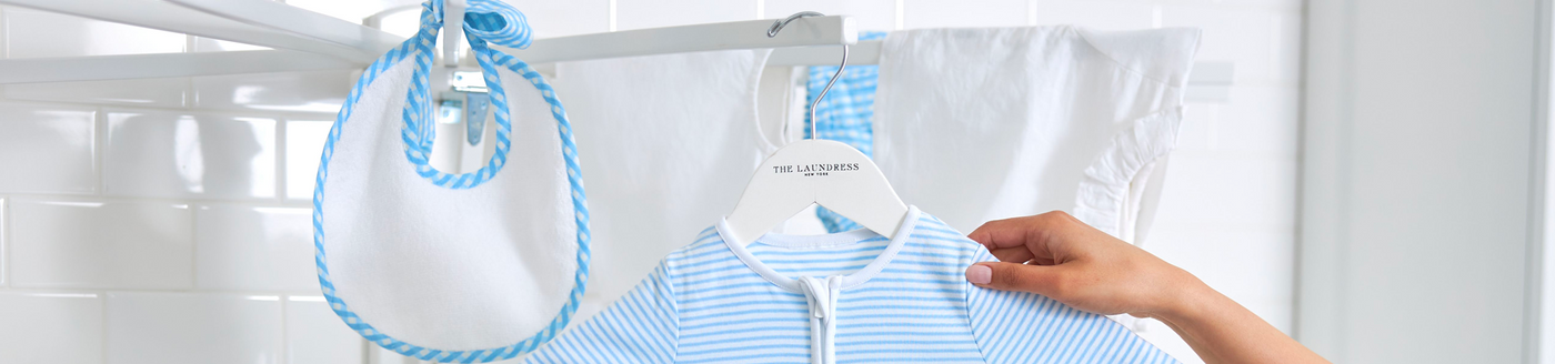 Baby clothes that were laundered using The Laundress Fragrance Free Baby Laundry Detergent being hung up in a closet. 