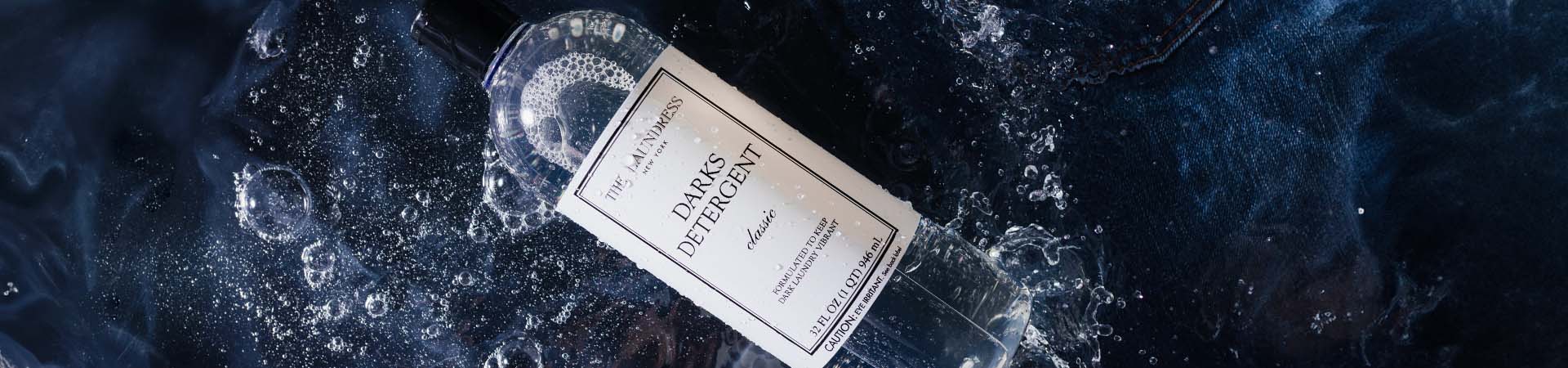 The Laundress Darks Detergent formulated to keep dark laundry vibrant laying in water with dark fabric.