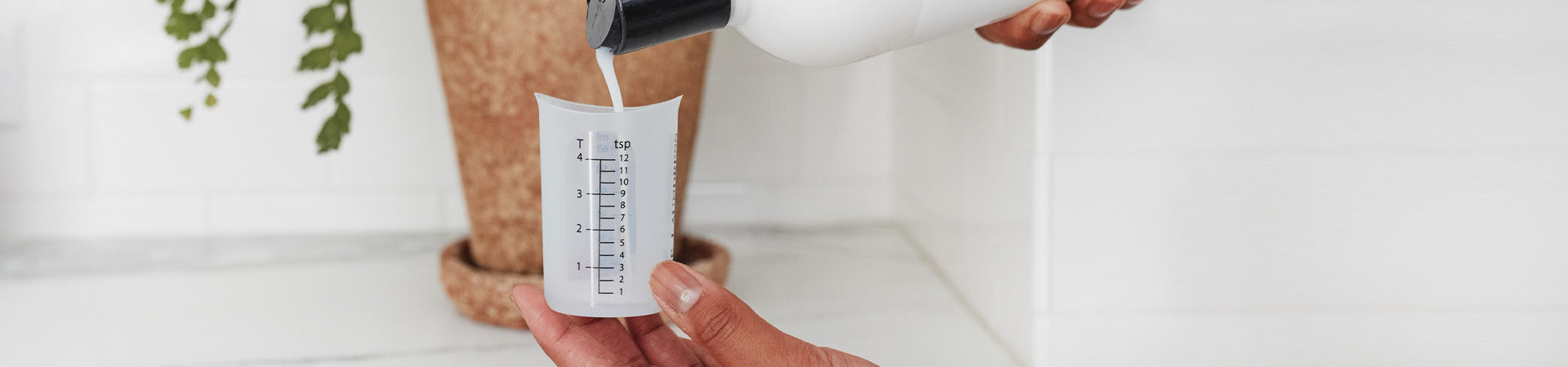 The Laundress bio-based liquid laundry detergent being poured in to The Laundress Laundry Measuring Cup.