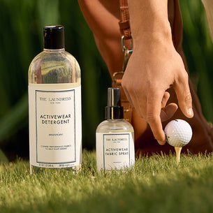 a person putting a golf ball on a golf ball next to a bottle of laundry detergent